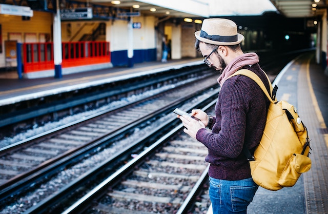 man checking mobile phone at train station