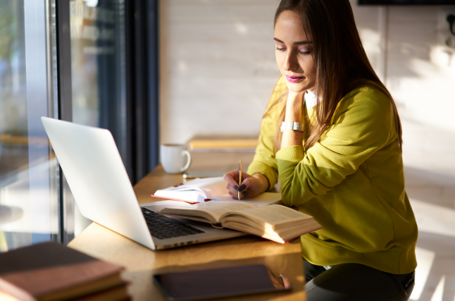 woman sat at a desk writing on a laptop