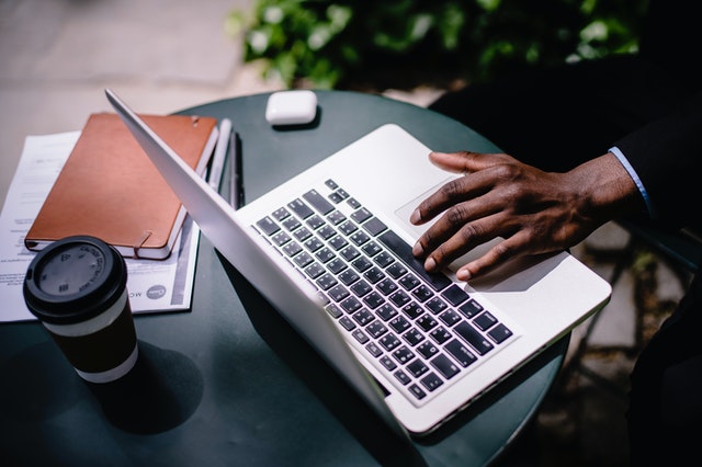 Person Writing on laptop while taking coffee