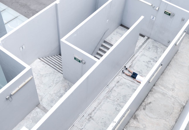 man lying down in walled maze