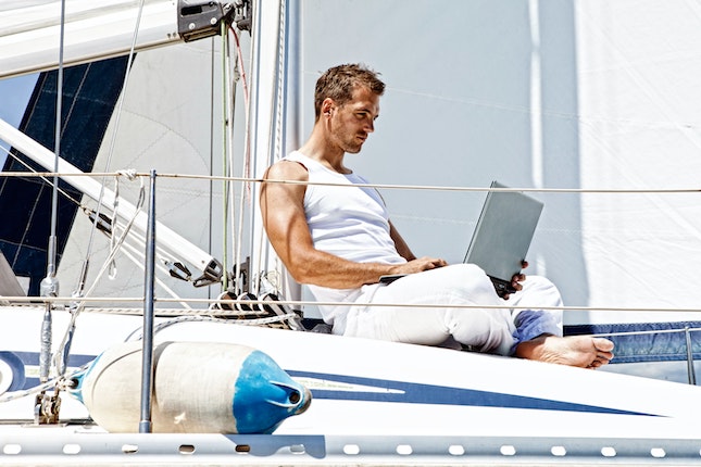 man writing on computer on sailing yacht