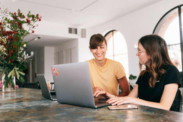 two women discuss over laptops