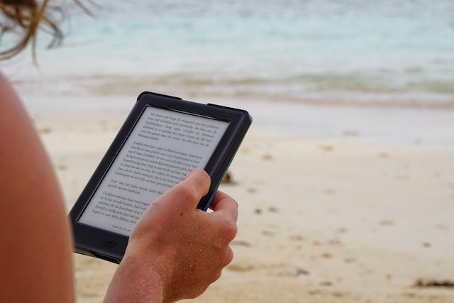 woman on a beach reading a kindle