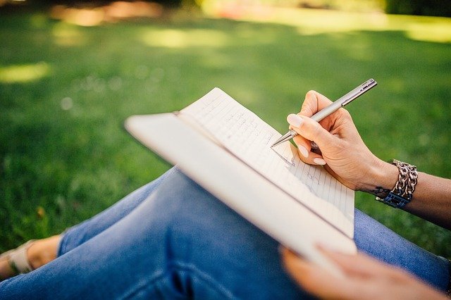 woman writing in notebook outside