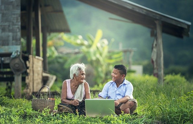 old woman and young boy talk in front of laptop