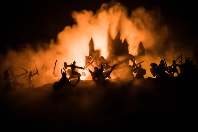 knights silhouetted against fire, shadow of a castle in the background