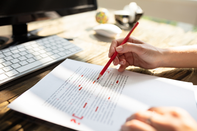 writer marking a manuscript with a red pencil