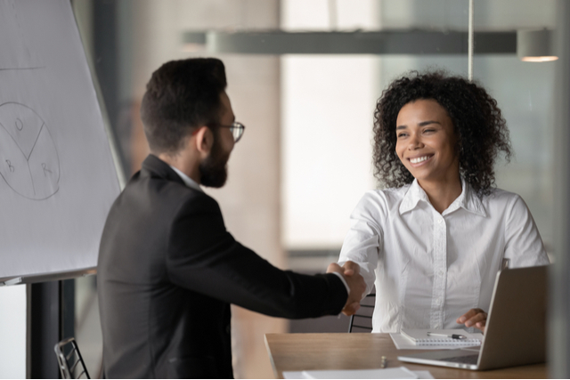 man and woman shake hands over some papers