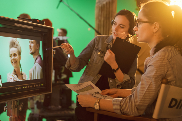 director watches filming while talking to producer