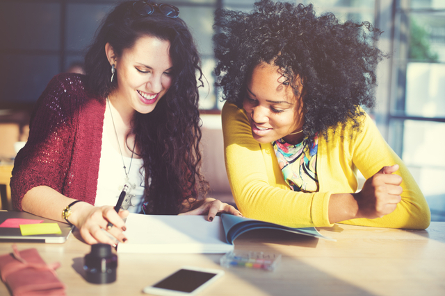 two women talking over a notebook