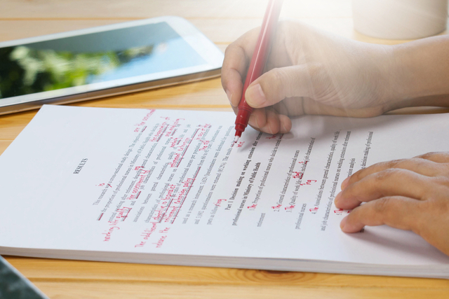 person self-edits manuscript with red pen