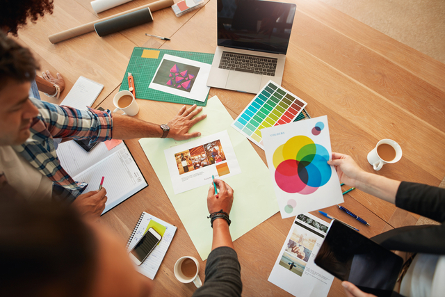 people sat around a desk working on advert designs