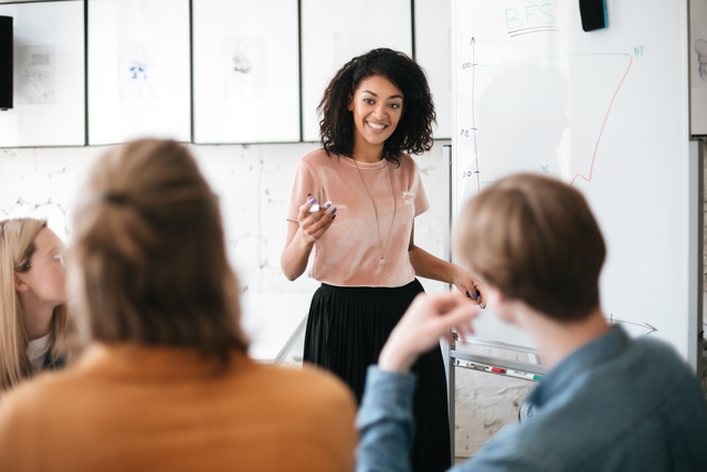 woman delegates responsibilities while writing on a whiteboard