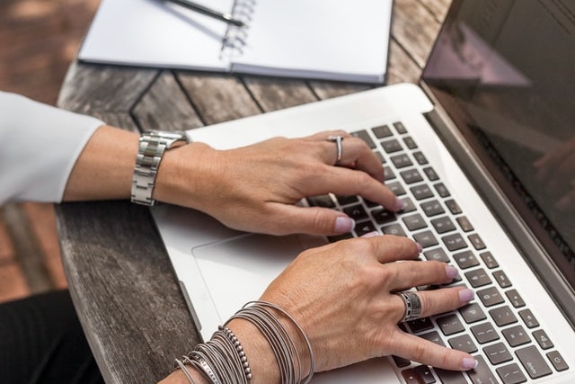 close up from above of woman's hands typing on a laptop